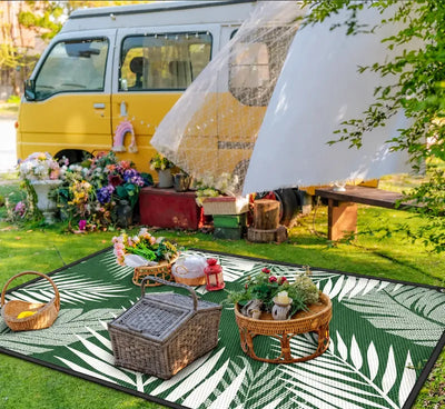 Tropical Design recycled camping mat featuring green and white palm leaf patterns with black binding, ideal for caravan awnings and outdoor camping.