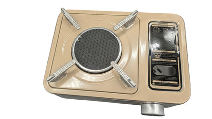 A vintage-style portable gas stove with a beige metal body, silver metal burner grates, and a black information and warning panel on the right side, photographed on a white surface.