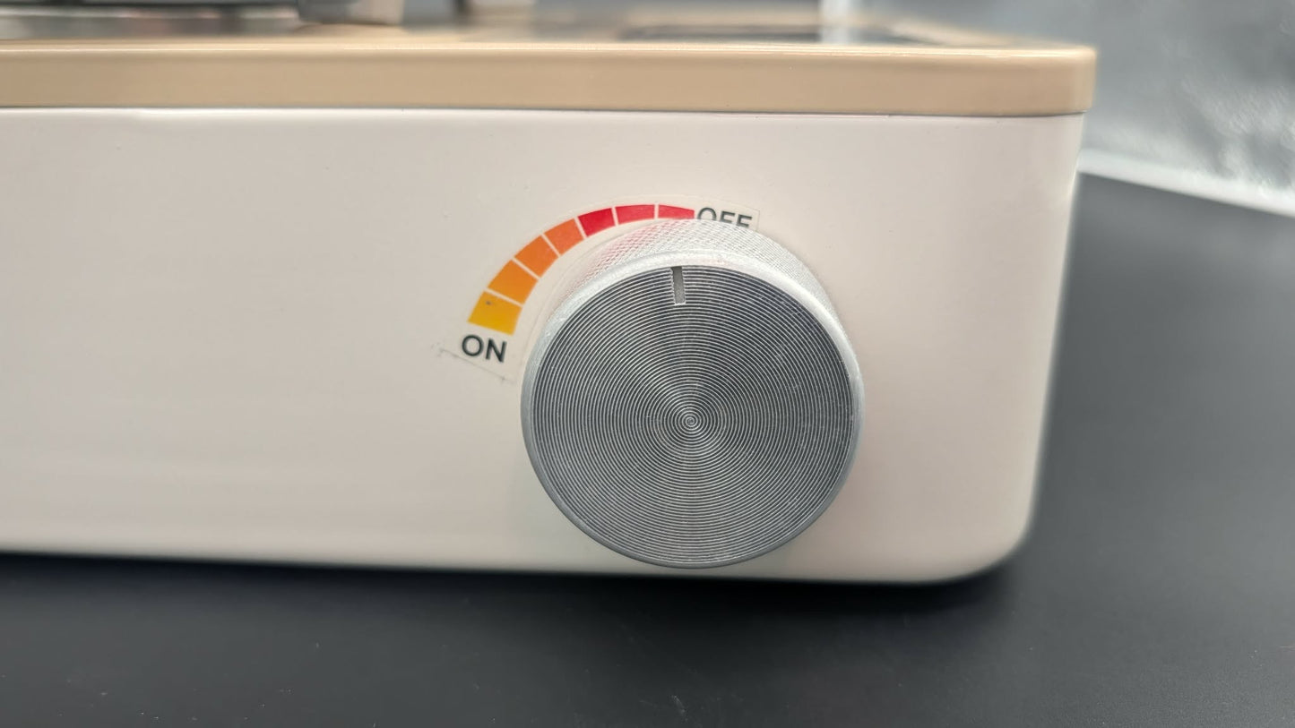 Close-up of a white appliance control panel with a round silver dial and a small orange-to-red arc labeled ON to OFF.